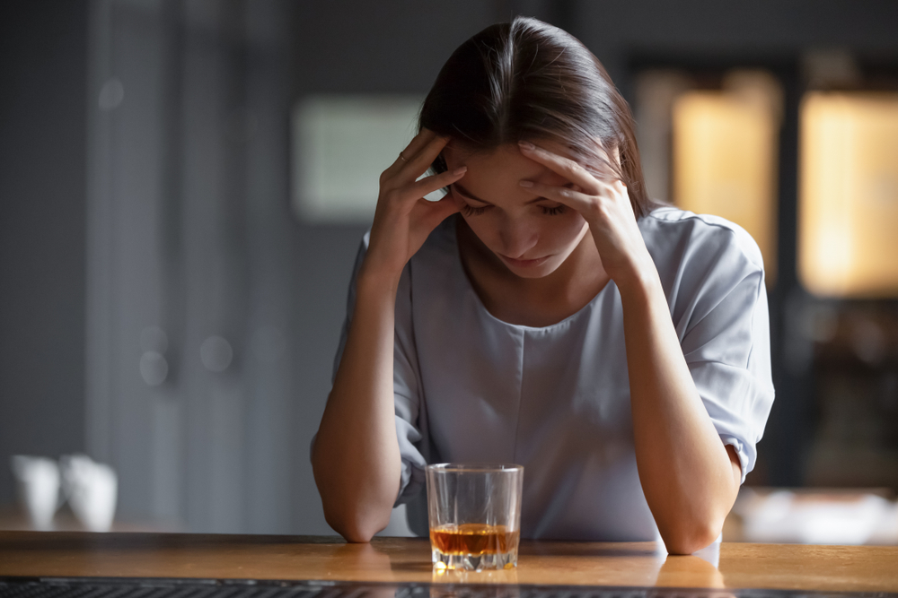 bolest hlavy a dívka, která má před sebou sklenku alkoholu